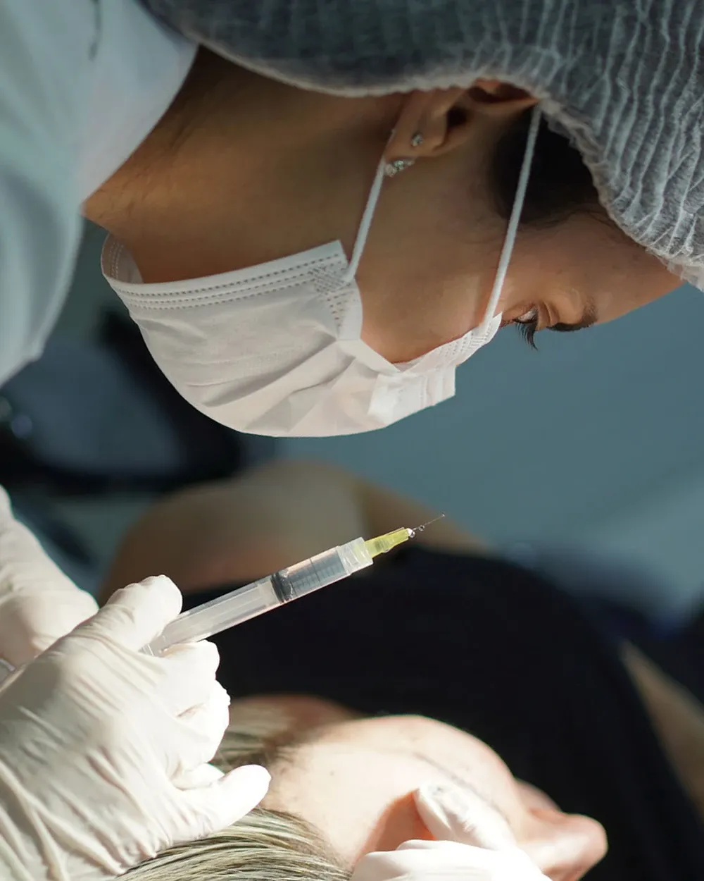 Residente examinando paciente com dermatoscópio sob a supervisão de uma especialista na Clínica Escola BWS
